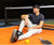 Image of Dekel Bar sitting down and leaning against a JOOLA Pickleball net.