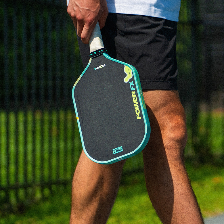 Close up on the JOOLA Power FX pickleball paddle by the legs of a male pickleball player.