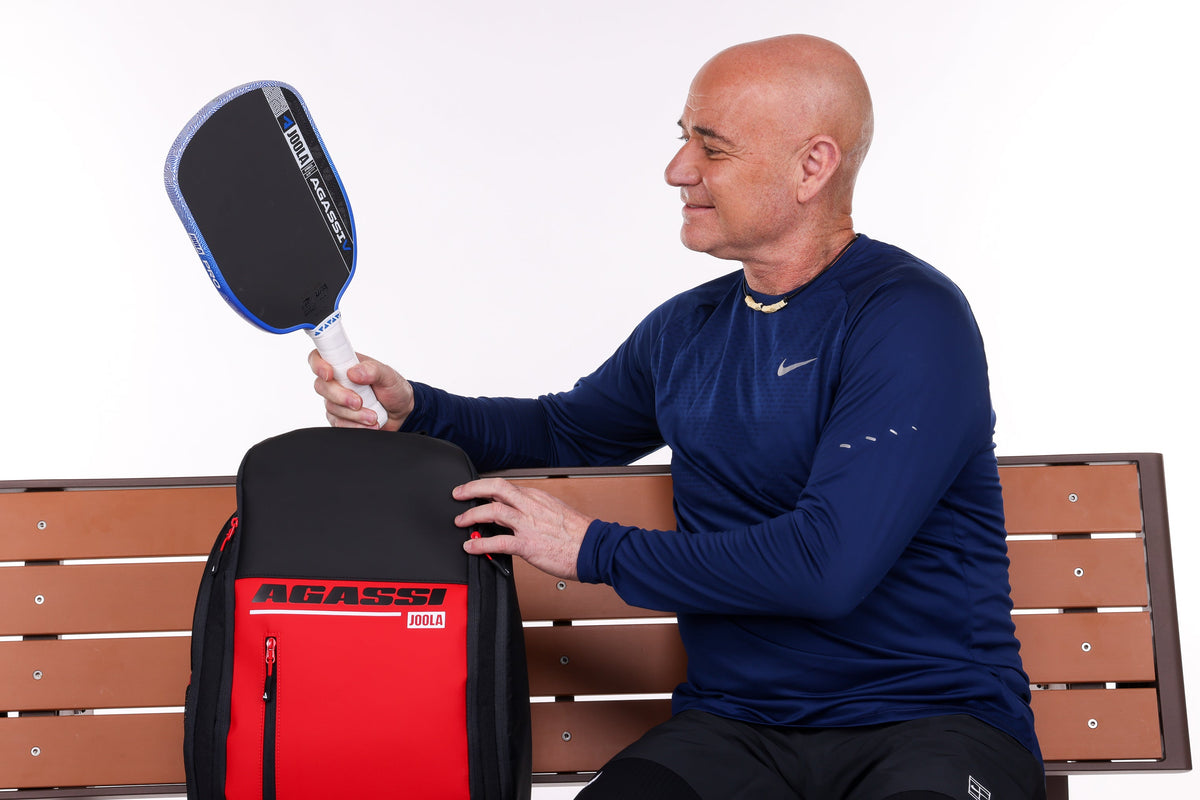Tennis icon Andre Agassi pulling an Agassi Pro V from an Agassi Deluxe pickleball bag.