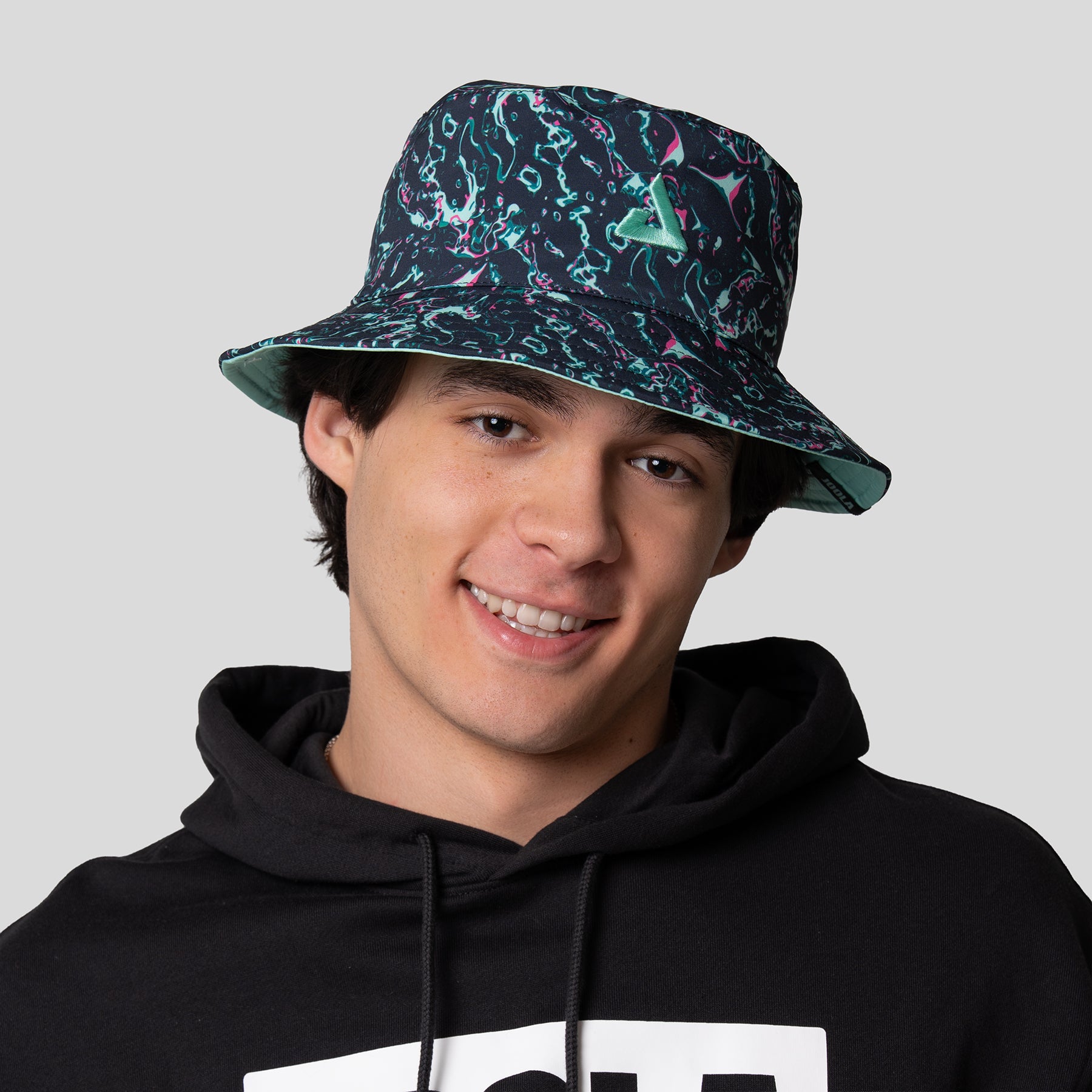 Image of a male model wearing a Aqua Synth pattern JOOLA Bucket hat.