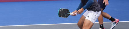 Horizontal banner image of a JOOLA pro holding a JOOLA pickleball paddle out on the Pickleball court.