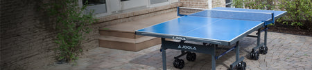 Horizontal banner image of an outdoor JOOLA Table Tennis table on an outdoor patio.