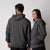 Male and female models wearing the JOOLA Unisex Fleece Hoodie, Charcoal Heather.