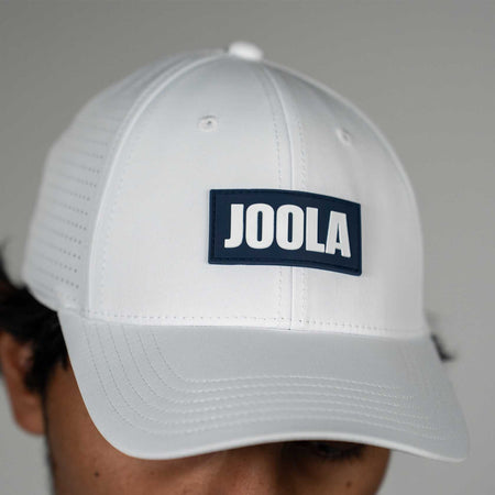 White cap with JOOLA logo on a gray background.