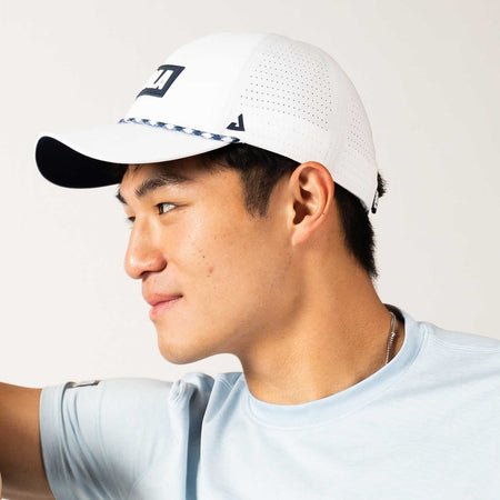Side profile of a man wearing a White and Blue JOOLA perforated rope cap.