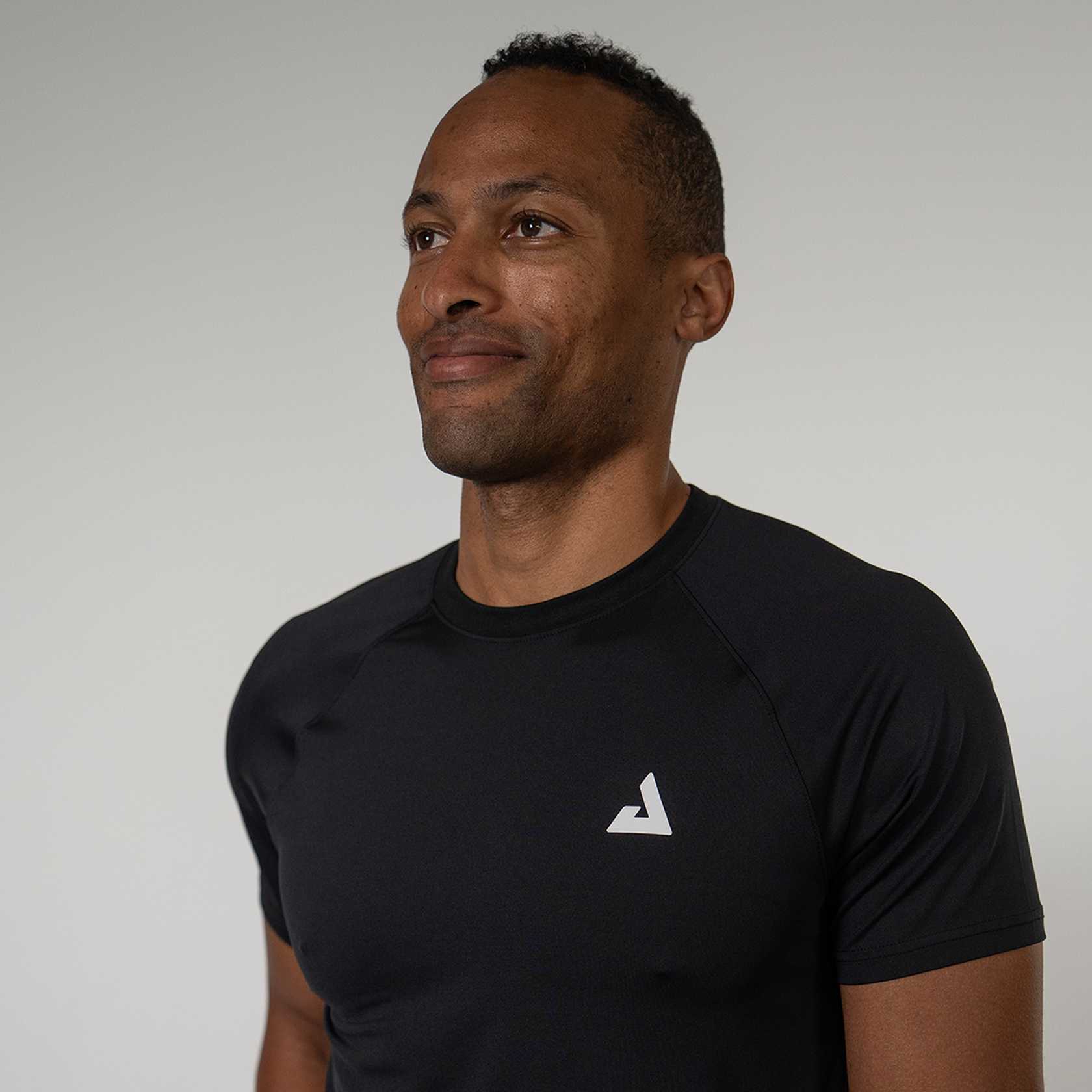 Man wearing a black  t-shirt with a white JOOLA Trinity logo on a plain background