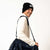 Man wearing a black beanie with 'JOOLA' logo and holding a navy bag on a white background