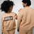 Two people wearing matching latte colored sweatsuits with 'JOOLA' branding on a plain background