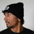 Person wearing a black beanie with a JOOLA logo on a plain background