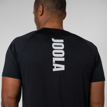 Person wearing a black t-shirt with JOOLA printed on the back against a plain background