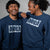 Two people wearing navy blue fleece sweatshirts with JOOLA logo on a gray background