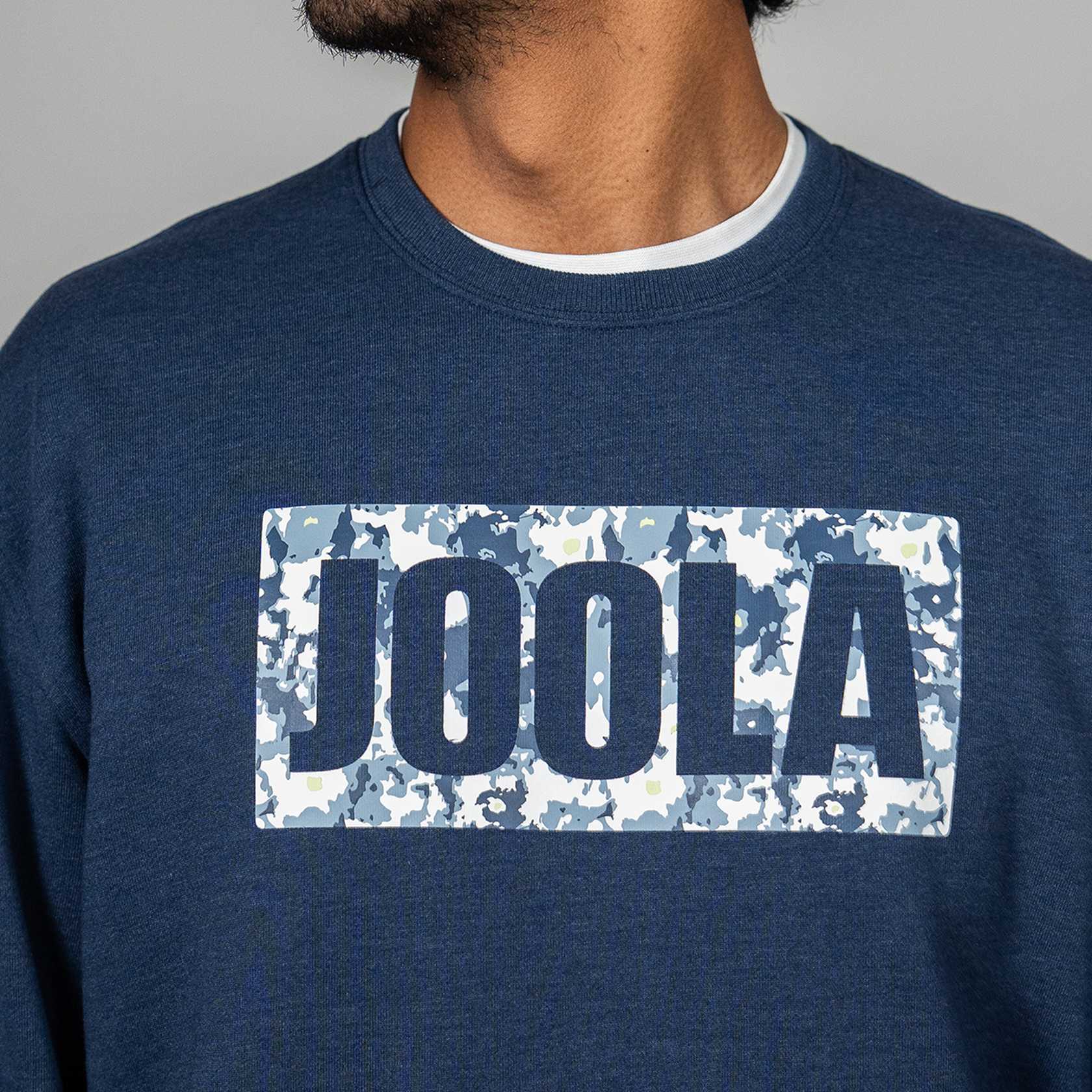 Close up of the JOOLA brand logo on a navy blue JOOLA Fleece sweatshirt.