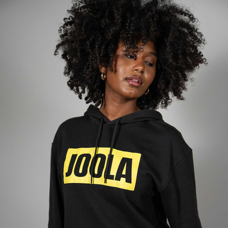 Person wearing a black hoodie with JOOLA logo on a gray background
