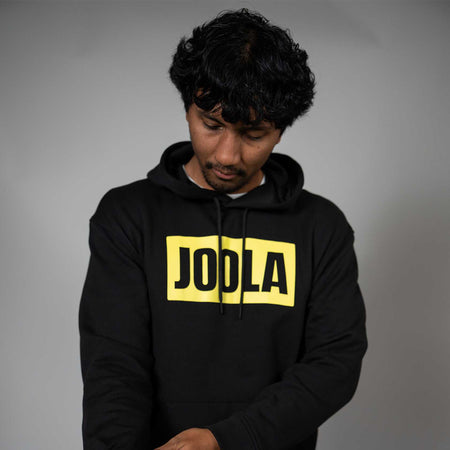 Person wearing a black hoodie with 'JODLA' in yellow on a gray background