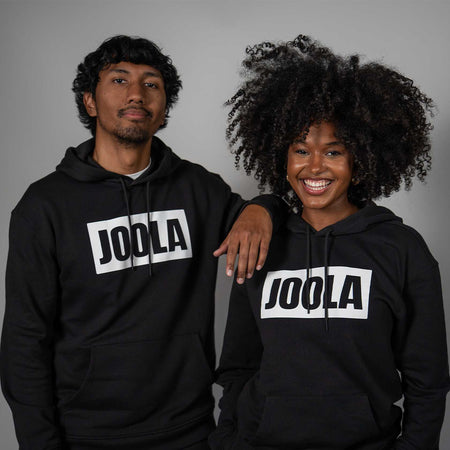 Two people wearing black hoodies with 'JOOLA' logo on a gray background.
