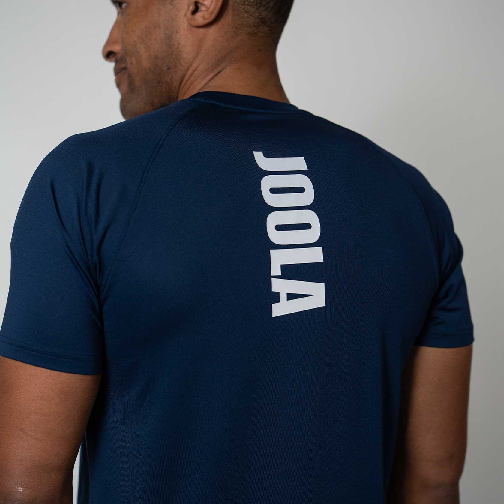 Person wearing a navy blue t-shirt with JOOLA branding on the back against a plain background