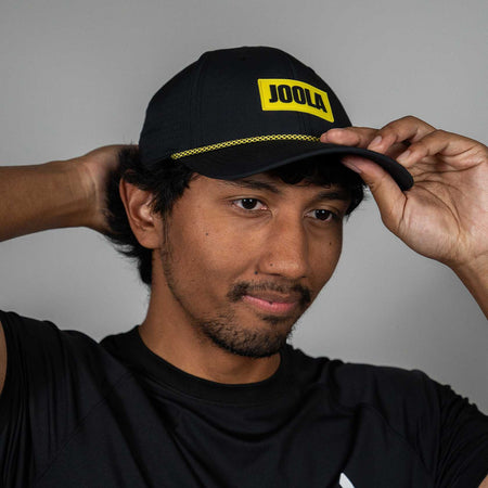 Person wearing the JOOLA Perforated Rope Cap. Black and Yellow.