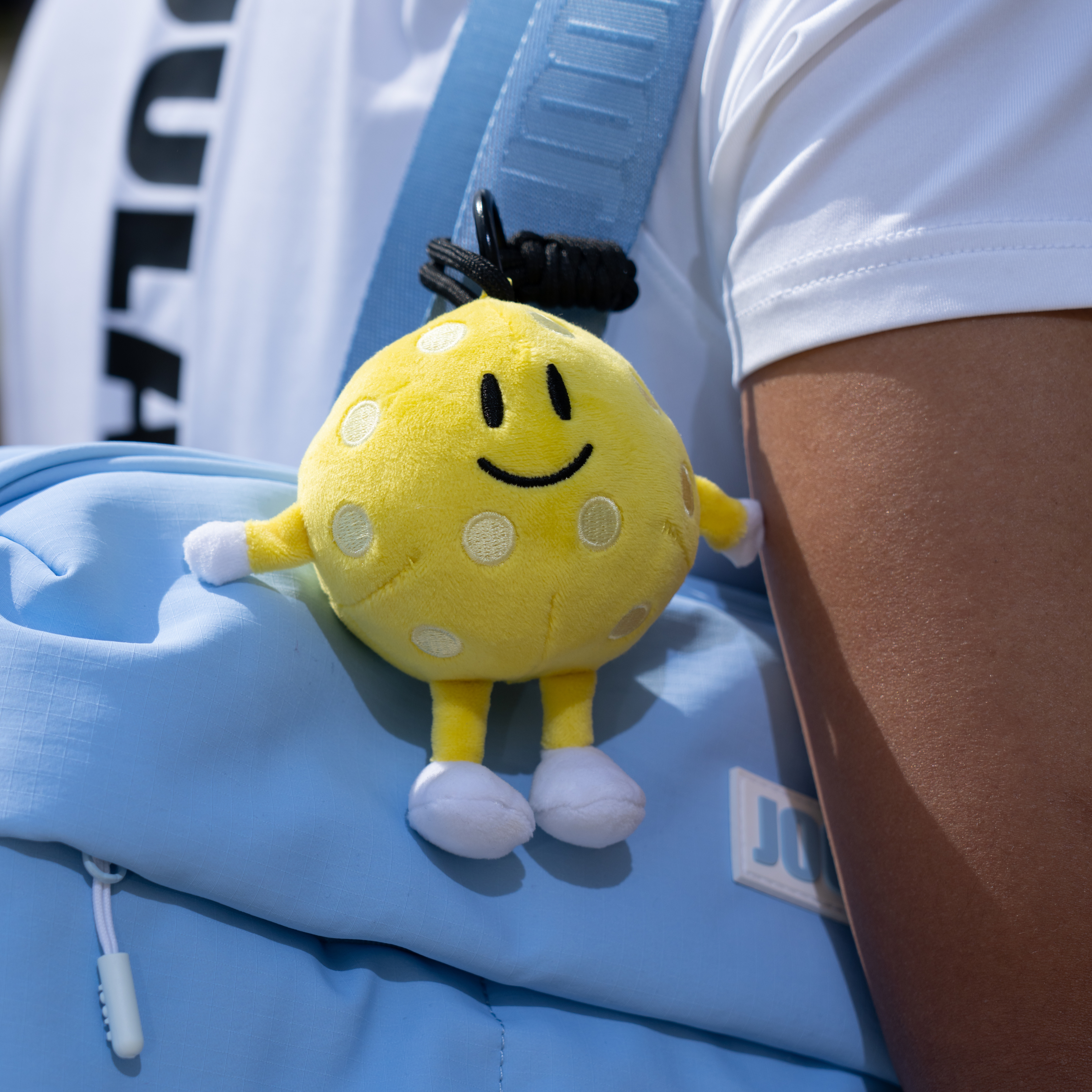 JOOLA's pickleball plushie clupped on to a JOOLA bag.