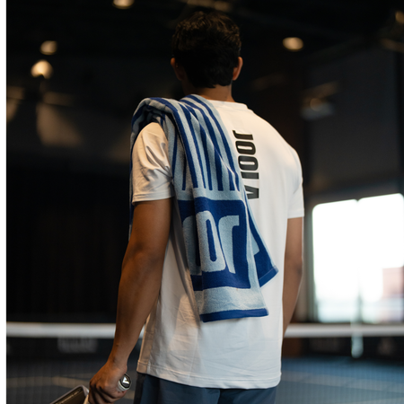 Image of a male pickleball player with a blue JOOLA Wordmark towel over his shoulder.