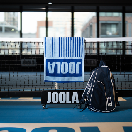 Image of the blue JOOLA work mark towel handing over a JOOLA pickleball net.