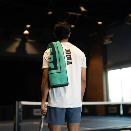 Image of a male pickleball player wearing a JOOLA green wordmark towel.
