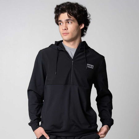 Gray background, model wearing a black JOOLA Half Zip.