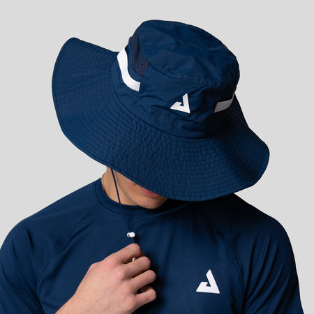 Man wearing a navy blue JOOLA wide brim hat with black accents on a light gray background