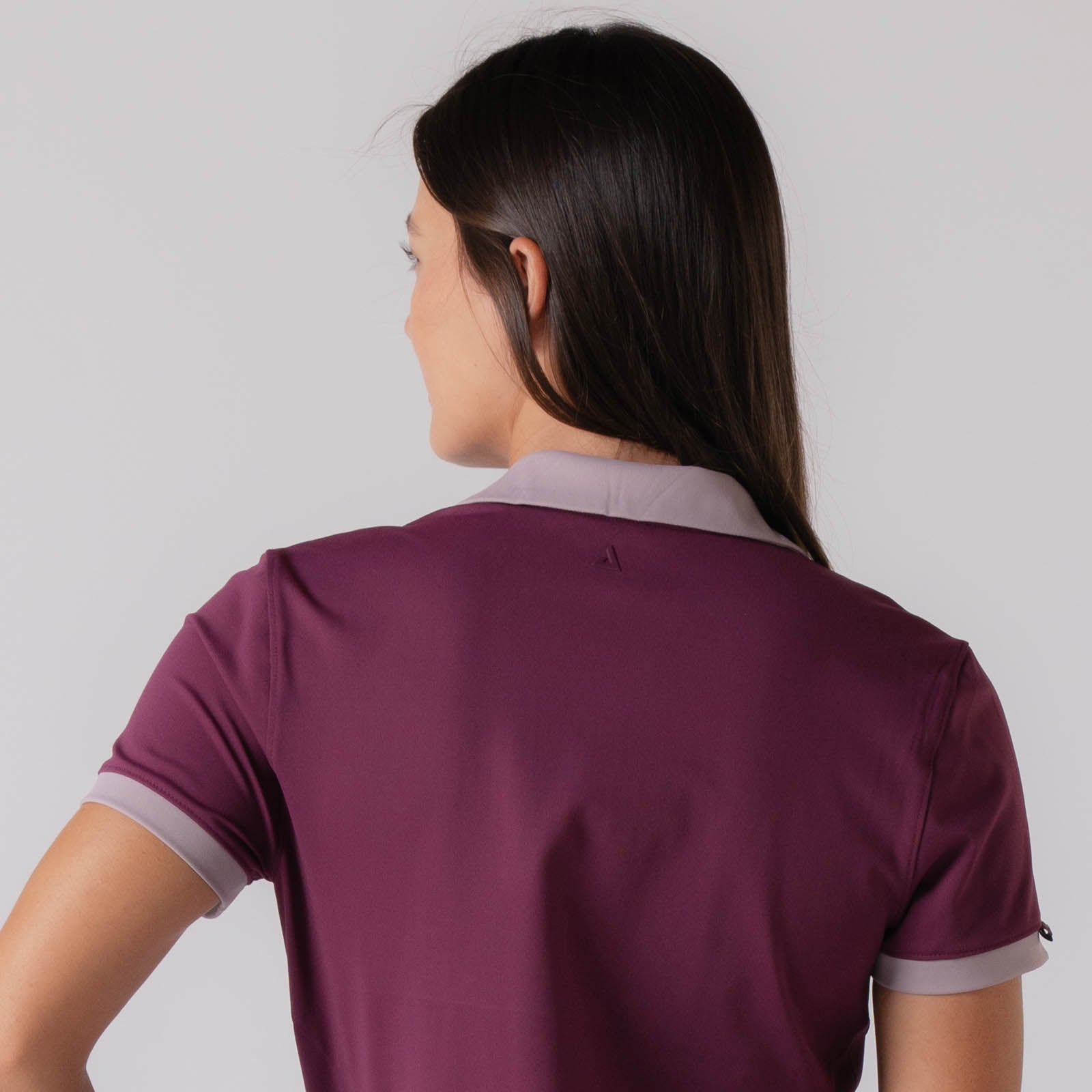 Close up image showing the back of a female model who is wearing a JOOLA Women's Club Polo Dress, Bordeaux.