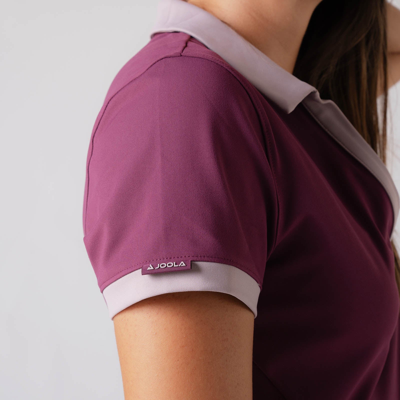 Close up image showing the JOOLA logo on the right sleeve of a JOOLA Women's Club Polo Dress, Bordeaux. 