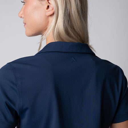 Close up image showing the raised JOOLA trinity logo detail on the back of a JOOLA Women's Club Polo Dress, Navy.