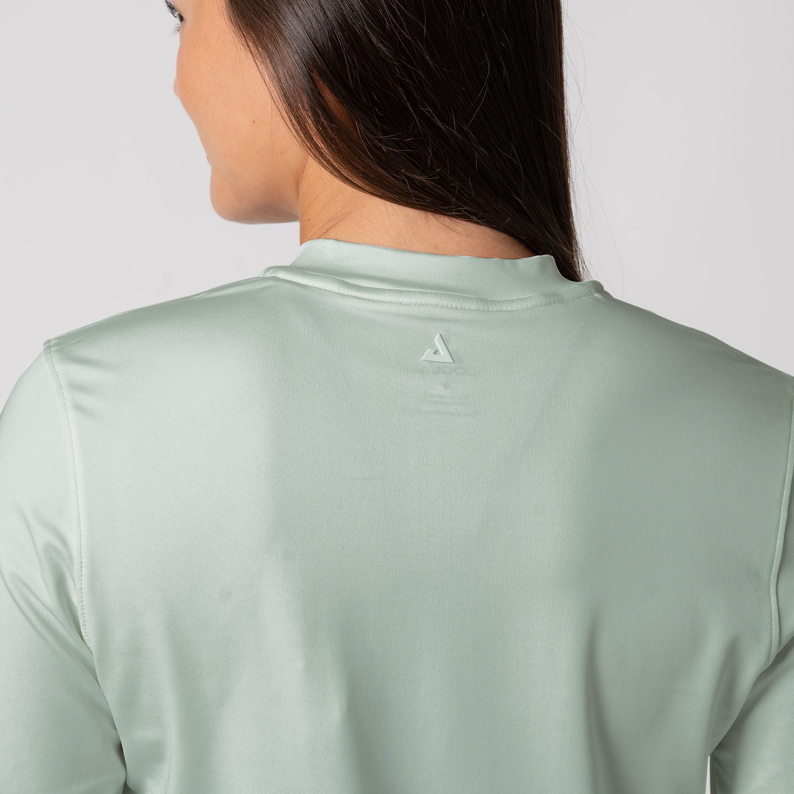 Close up image showing the raised detail of the JOOLA trinity logo on the back of a JOOLA Women's Quarter Zip Pullover, Hushed Mint.