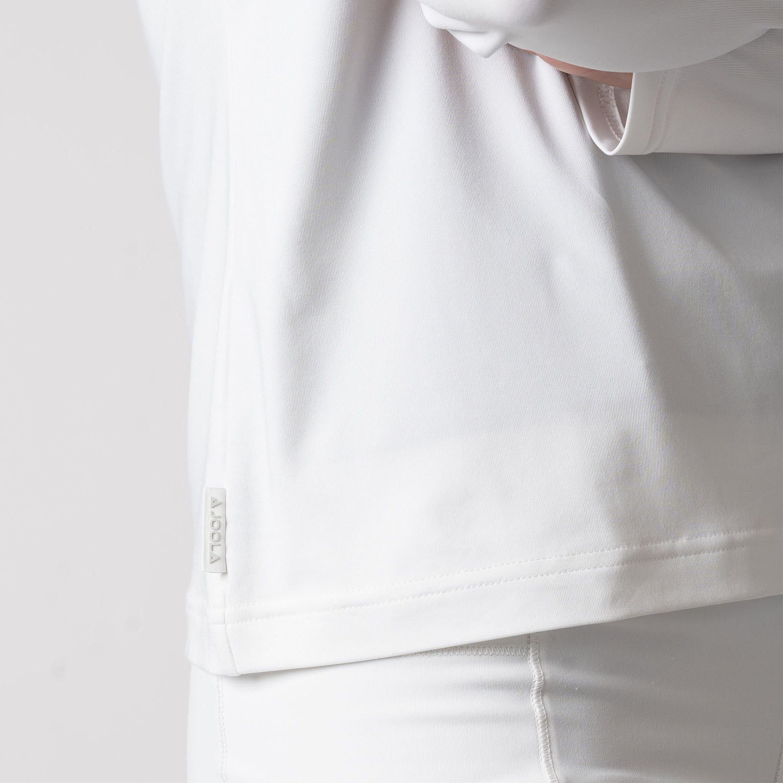 Image showing the raised JOOLA logo tag on the side of a JOOLA Women's Quarter Zip Pullover, White.