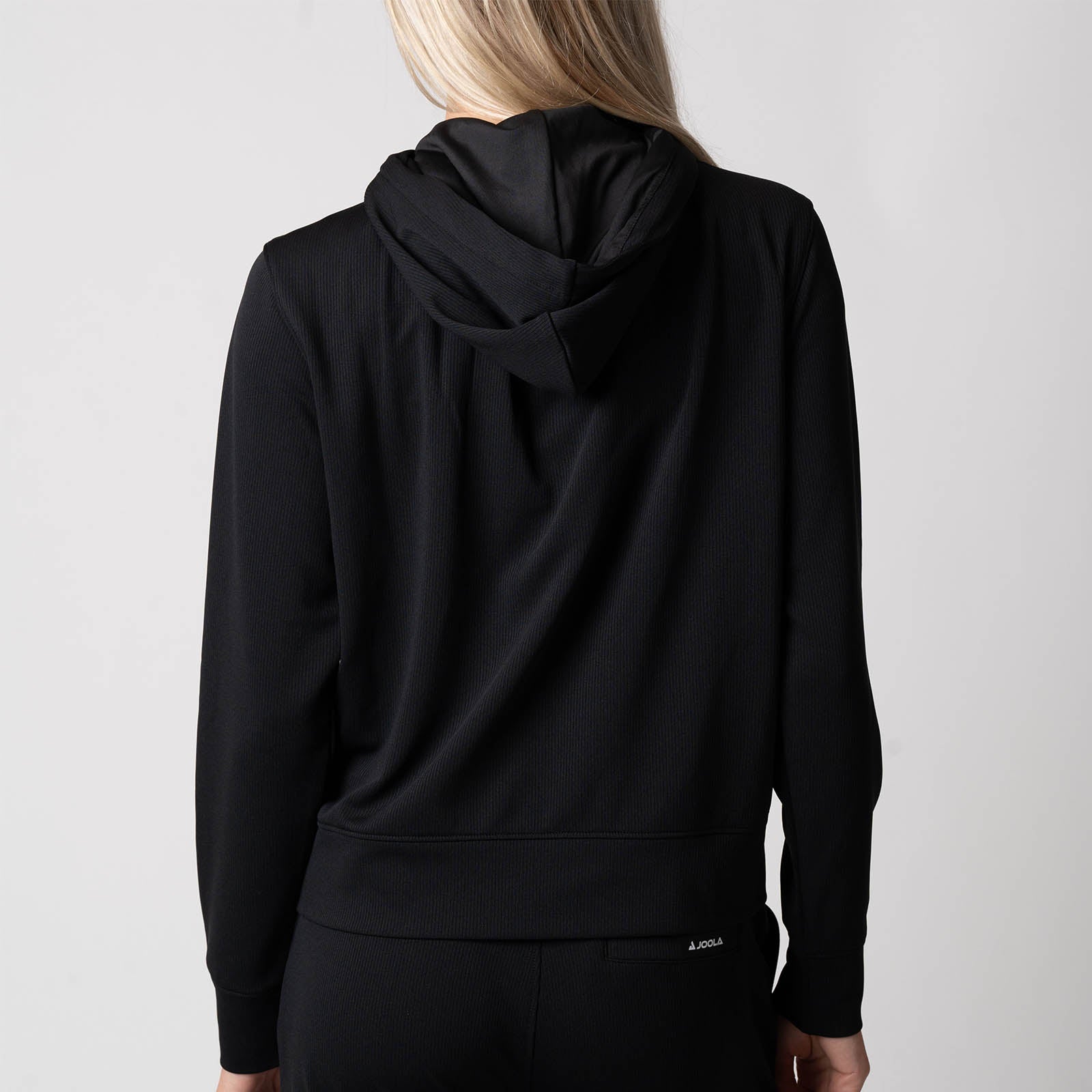 Image showing the back of a JOOLA Women's Ribbed Jacket showing the hood, black.