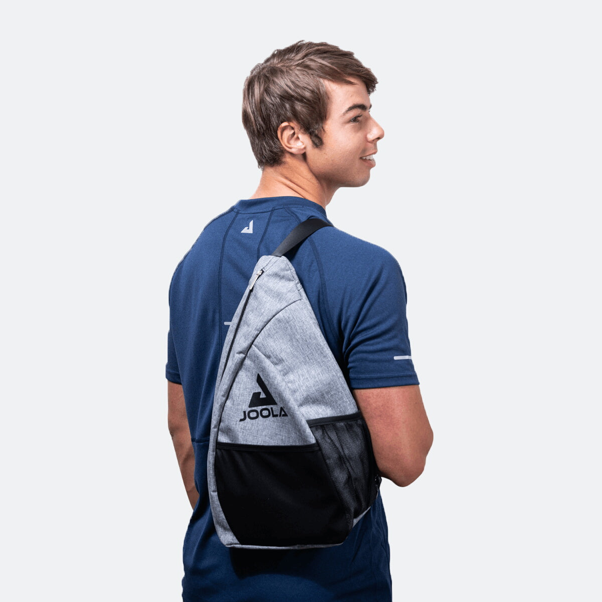 White Background Image: Image of Ben Johns wearing the JOOLA Essentials Sling Bag over his shoulder.