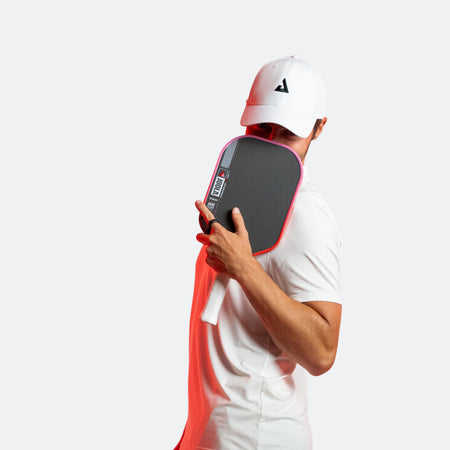 White and pink gradient background, image of JOOLA Pro Ben Johns holding a Perseus Pro IV over his face. 