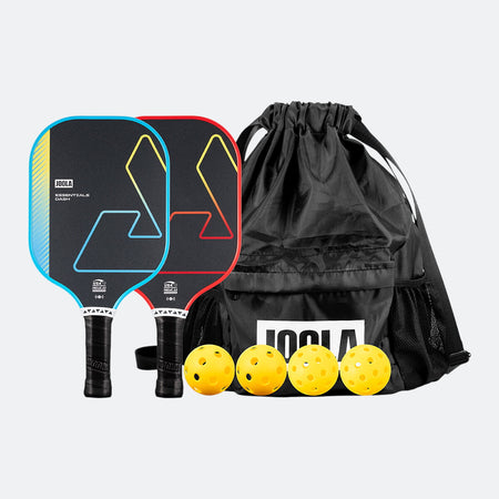 White background photo, one blue Essentials Dash pickleball paddle, one red essentials dash pickleball paddle, a JOOLA branded carrying bag and four yellow pickleballs.
