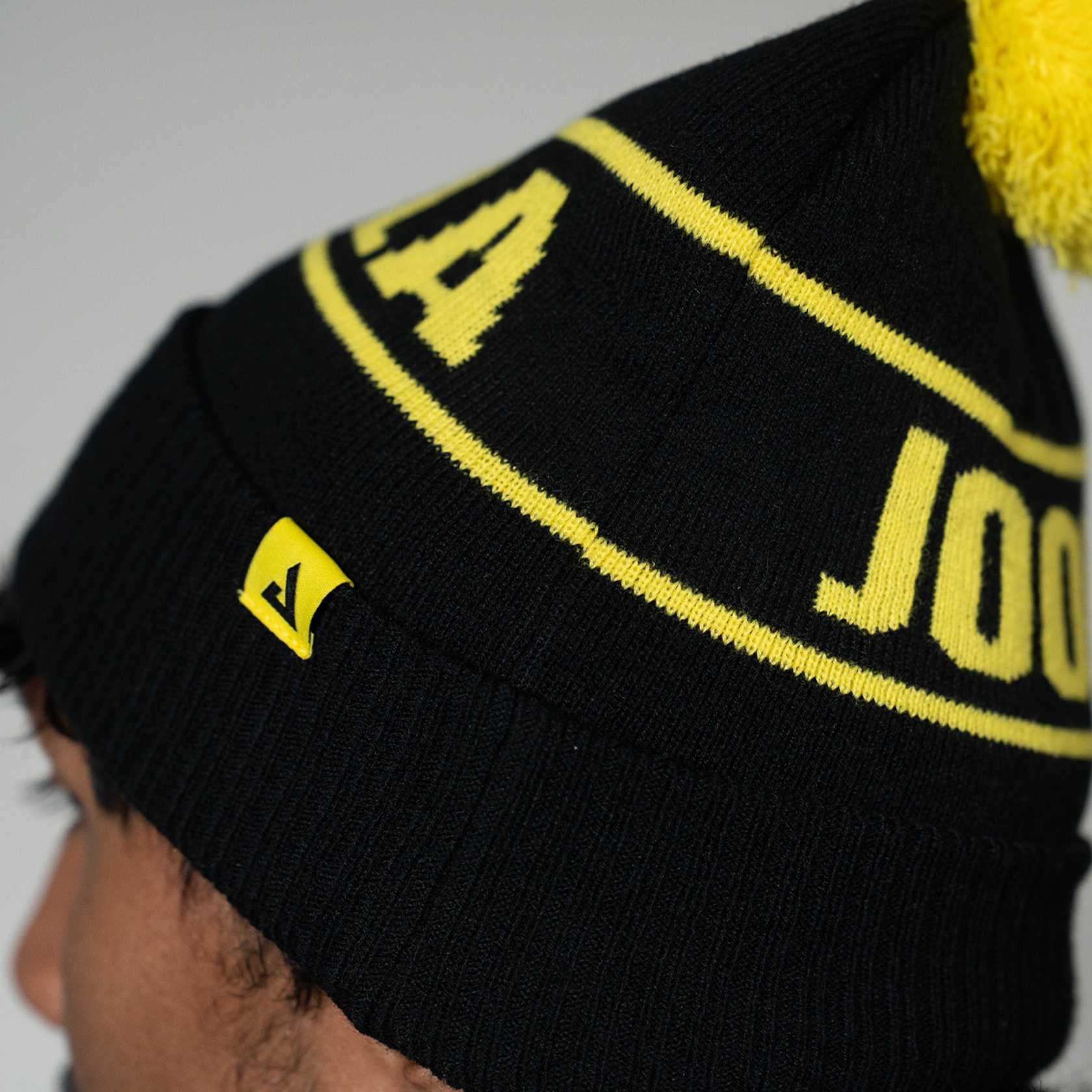 Close up image of the JOOLA winter beanie, black and yellow.