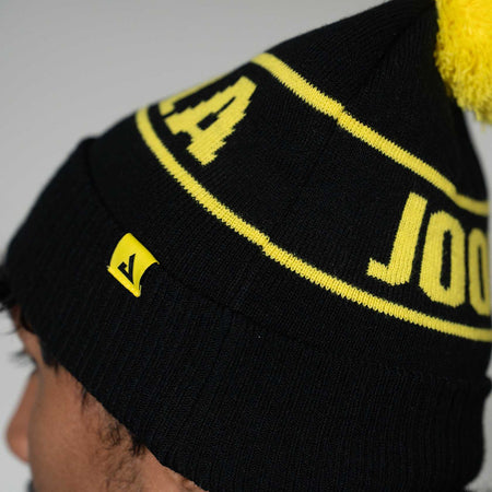 Close up image of the JOOLA winter beanie, black and yellow.