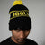 Person wearing a black beanie with yellow JOOLA text and pom-pom on a gray background