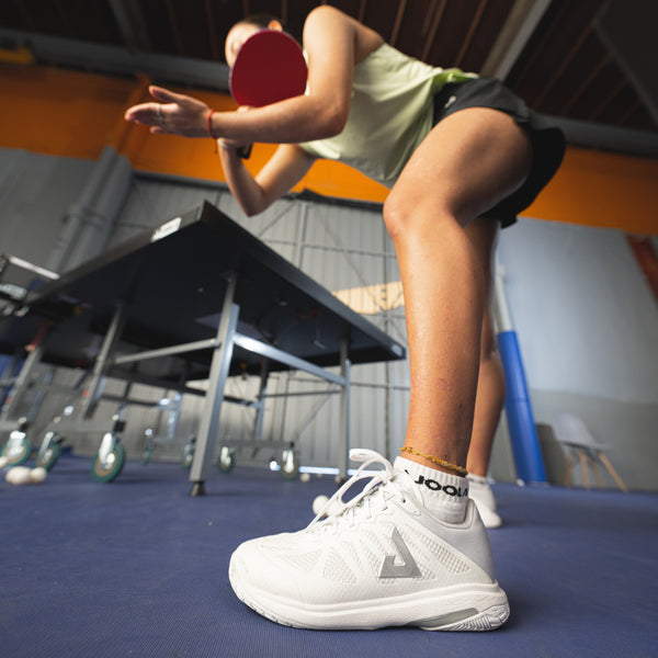 Close up on a shot of the JOOLA TT SM4SH table tennis shoe on a table tennis player at an indoor table tennis facility.
