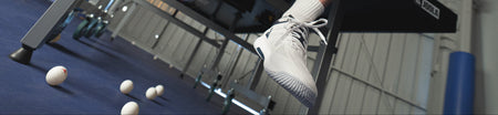 Horizontal banner image showing the JOOLA TT SM4SH table tennis shoe with table tennis balls on the floor.